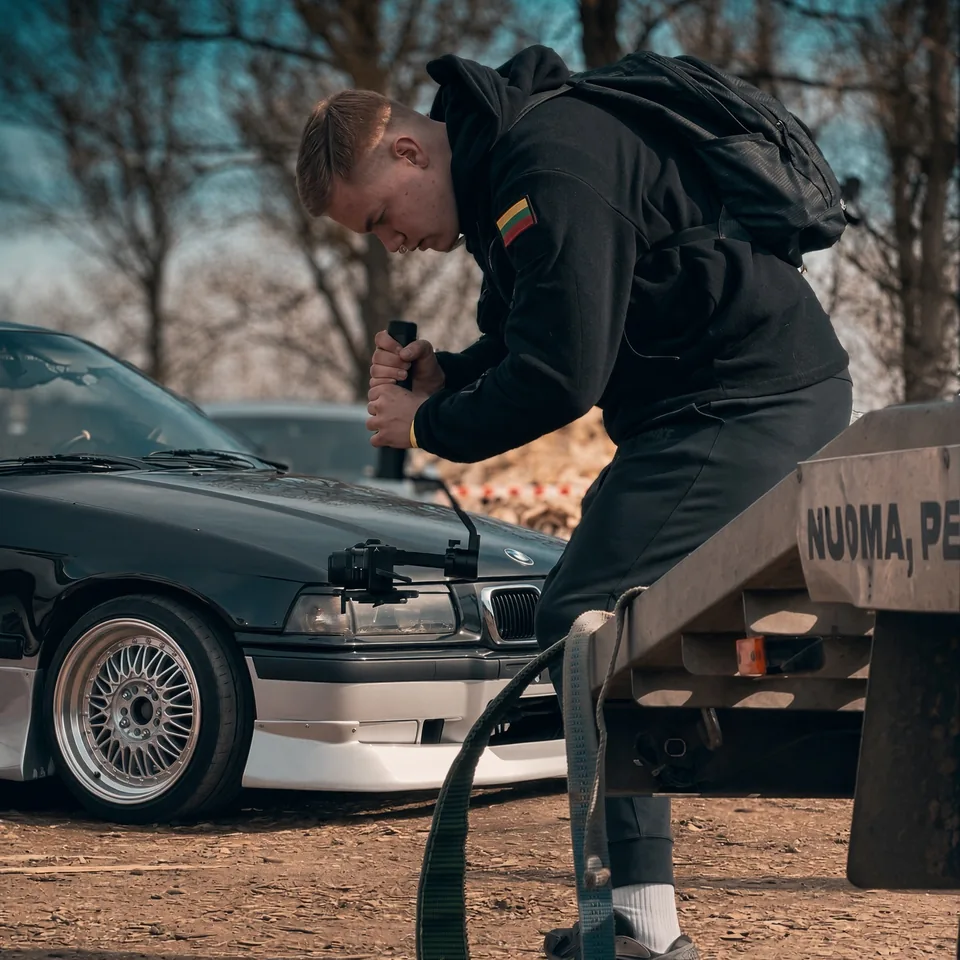 Operatorius su gimbalu filmuoja juodą BMW E36